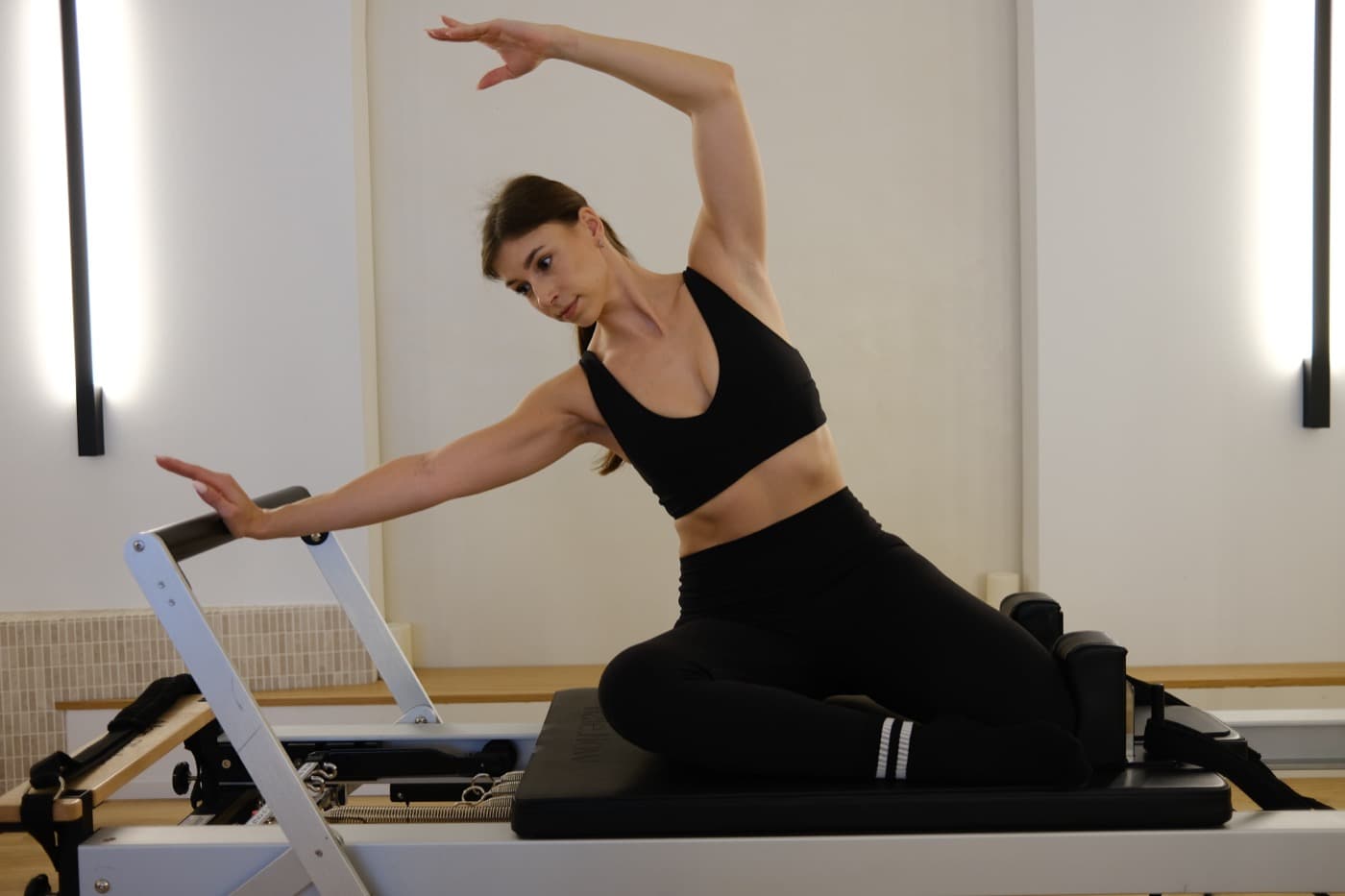 Reformer Pilates Übung: Seitbeuge zur Wirbelsäulenmobilität — Trainerin auf dem Reformer